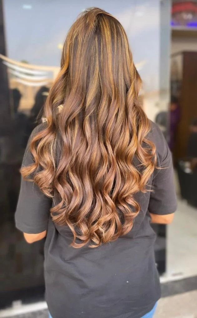 Long balayage curls with caramel highlights at Royal Look